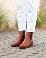 Botas estilo Chelsea de cuero vacuno color marrón con textura grabada tipo reptil. Presentan paneles elásticos laterales en color negro, puntera almendrada y taco cuadrado de madera.