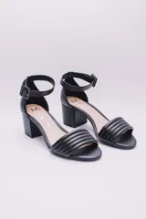Sandalias negras de ecocuero con pulsera al tobillo y tacón cuadrado. La capellada es acolchada con diseño de líneas horizontales.