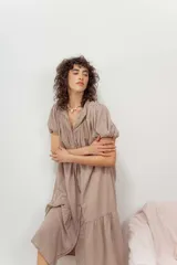 Vestido color beige con botones frontales, cuello camisero, mangas cortas abullonadas y falda con volantes.