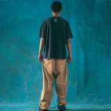 Remera negra de corte oversize con efecto lavado y estampado frontal con un diseño gráfico que incluye un logo con las letras 'KI', un dibujo de una casa y el número '420'.