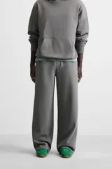 Pantalón jogger negro de corte ancho, confeccionado en tejido de algodón con interior de rizo. Cuenta con cintura elástica ajustable con cordón interior, bolsillos laterales y bolsillo trasero de parche.