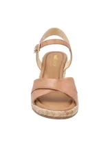 Sandalias con plataforma de yute color marrón claro, con dos tiras anchas cruzadas de cuero marrón y pulsera al tobillo con hebilla dorada.