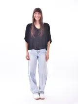 Blusa negra con cuello redondo y abotonadura frontal parcial. Tiene mangas cortas amplias y corte holgado.