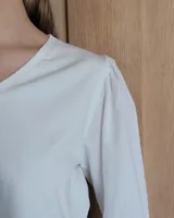Blusa blanca de mangas 3/4 abullonadas con escote en V.