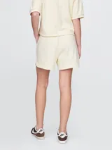 Short deportivo color crema, con cintura elástica ajustable con cordón y logo bordado en la pierna izquierda.