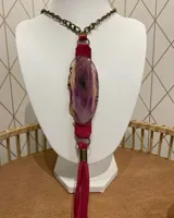 Collar con cadena de eslabones color bronce, tira de gamuza fucsia y dije de piedra natural veteada en tonos lila y beige.