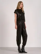 Enterito de silueta relajada confeccionado en tejido suave con lurex, color negro. Diseño de mangas cortas con escote a la base y laterales abiertos. Cintura elastizada y pantalón estilo jogger con terminación ajustada en el ruedo y bolsillos laterales.