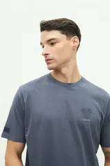 Remera blanca de manga corta con cuello redondo y estampado pequeño en el pecho con una columna griega y texto en color celeste.