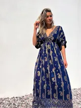 Vestido largo azul con estampado de cachemir dorado, escote en V, mangas cortas y cintura imperio con cordón ajustable.