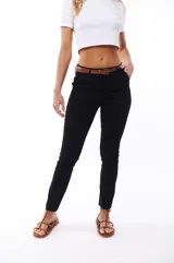 Pantalón negro de corte ajustado, con cinturón fino marrón.