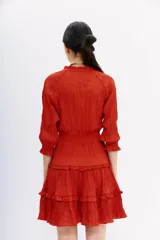 Vestido corto color ladrillo, de mangas largas con puños elásticos, escote en V y falda con volados.