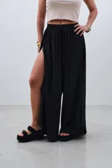 Pantalón palazzo negro con cintura elástica y aberturas laterales altas.
