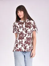 Remera estampada con motivos florales en tonos naranja, beige, gris y rosa.