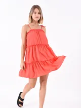 Vestido corto color naranja oscuro, con breteles finos y volados en el escote y en los cortes de la falda.