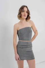 Minifalda negra ajustada al cuerpo, confeccionada en tejido elástico con strass plateado.