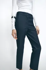 Pantalón tobillero azul oscuro, de tiro medio con cintura elástica en la espalda. Tiene bolsillos delanteros y falsos bolsillos de vivo en la parte trasera. El bajo está acabado con aberturas laterales.