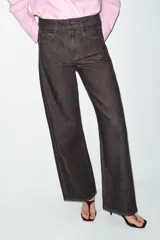 Jeans de tiro medio, color negro lavado con efecto desgastado, corte recto y holgado (loose straight), con cinco bolsillos y cierre frontal de cremallera y botón.