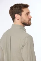 Camisa de lino color beige, de manga larga, con cuello clásico y bolsillo en el pecho.