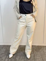 Pantalón de cuero sintético color beige, de corte recto, con bolsillos laterales y botón frontal.