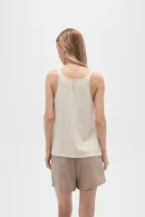 Musculosa color crema de bretel fino con apliques de cadena en los breteles y escote en V.