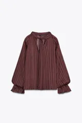 Blusa color marrón con rayas verticales, cuello subido con lazo, escote pico, mangas largas abullonadas con elástico en los puños y cierre frontal con botones forrados.