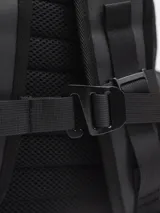 Mochila negra con cierre superior y bolsillo frontal con cierre. Tiene dos bolsillos laterales con cierre y un pequeño logo cuadrado en la parte inferior.