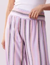 Pantalón wide leg de lino con cintura elastizada y estampado a rayas verticales en tonos lila, rosa, gris y blanco.