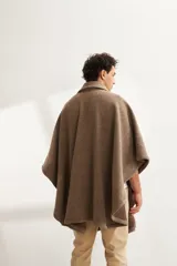 Poncho unisex de lana fina color marrón claro, con cuello polo, cartera con broches a presión y bolsillo ojal.