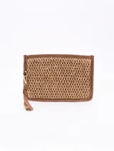 Monedero tipo sobre de paja trenzada color arena, con borde y correa de mano marrón.