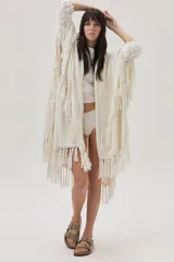 Ruana tejida color crema con flecos y lurex dorado.
