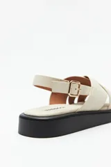 Sandalias negras de símil cuero con agarre ajustable en el talón y capellada entrelazada. Plataforma de 3 cm de alto.