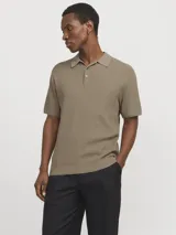 Polo de punto color beige, con cuello clásico, mangas cortas y cierre con botones.