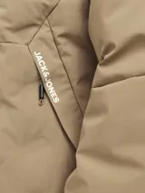 Campera híbrida color caqui, ligera e impermeable, con capucha, cierre frontal con cremallera, mangas largas con puños elásticos y bolsillos frontales con cierre.