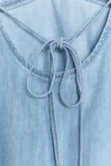 Top celeste de denim con escote en pico y tirantes finos regulables.
