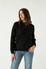 Sweater negro de punto suave con cuello redondo y hombros caídos.