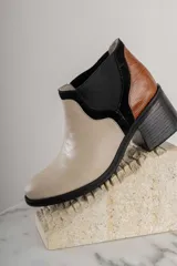 Bota corta de cuero sintético negro con elástico lateral y detalle de estampado animal print en el talón.