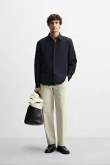 Camisa azul marino de corte regular fit, confeccionada en tejido de algodón con estructura. Tiene cuello solapa, manga larga con puños abotonados y cierre frontal con botones.