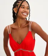 Vestido corto rojo de lino con tirantes dobles y costuras en contraste. Tiene una abertura debajo del busto y pespuntes vistos en el ruedo.