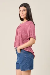 Blusa color rosado con estampado de hojas blancas, cuello redondo con detalle de pinzas y mangas cortas.