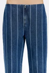 Pantalón denim azul con rayas verticales blancas, corte recto, largo tobillero y bajo desflecado.