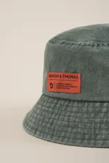 Gorro tipo bucket color lila con etiqueta naranja con el logo de la marca Benson & Thomas.
