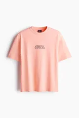 Remera color salmón de corte holgado, cuello redondo y manga corta. Estampado frontal con la frase "Currently Unavailable".