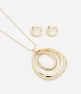 Conjunto de collar y aros dorados con diseño de círculos concéntricos. El collar tiene una cadena fina y un colgante con tres círculos de diferentes tamaños. Los aros son pequeños y tienen forma de círculo.