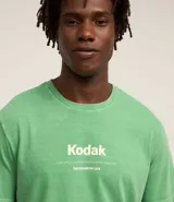 Remera verde con estampa de la marca Kodak y photoprint de playa paradisíaca.