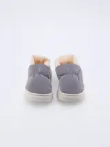 Pantuflas grises con interior de piel sintética color crema y suela blanca.