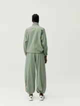 Pantalón estilo paracaídas color verde claro, de tejido técnico Wind_S, con bolsillos laterales y reguladores en la cinturilla y en el bajo.