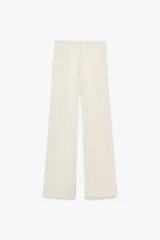 Pantalón de vestir color crema de tela satinada, corte palazzo y tiro alto.