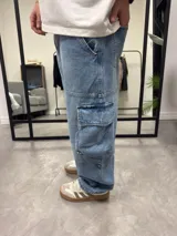 Pantalón de jean celeste, corte ancho, estilo cargo con bolsillos laterales.