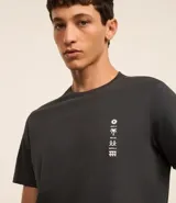 Remera negra de corte regular, cuello redondo y manga corta. Estampa minimalista vertical con caracteres japoneses en el lateral izquierdo del pecho.
