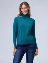 Polera de punto fino marca Nienty, color turquesa, con cuello alto, manga larga y detalle de tajo en los puños.